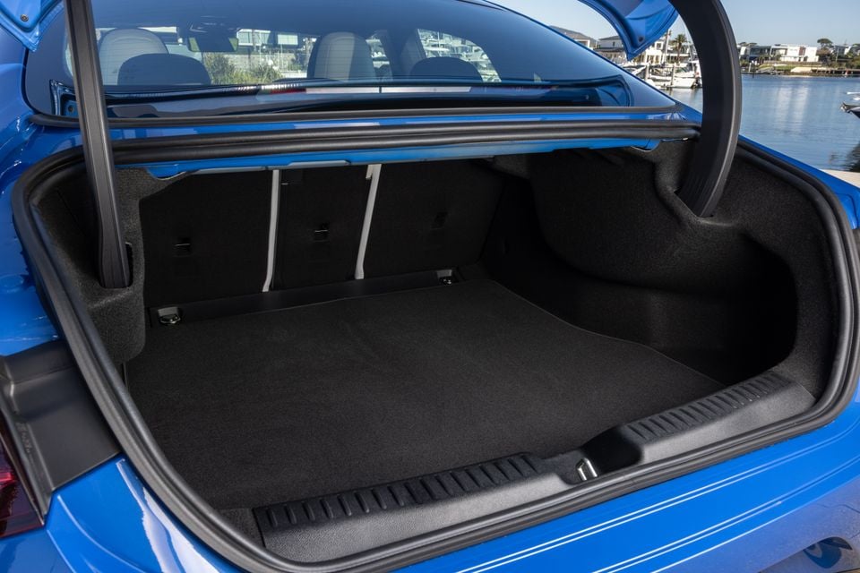 Open boot of a blue 2026 Mercedes-Benz CLA showing a carpeted, empty cargo area with folding rear seat backs visible