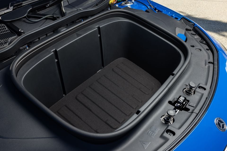 Open frunk (front boot) of a blue 2026 Mercedes-Benz CLA 250 Electric, showing a large empty storage compartment with a dark rubberised lining
