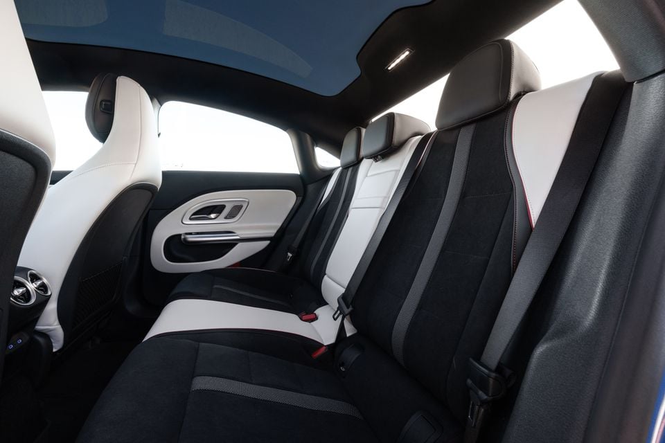 Rear seats of a 2026 Mercedes-Benz CLA, showing two-tone black and white upholstery with red contrast stitching and seatbelts