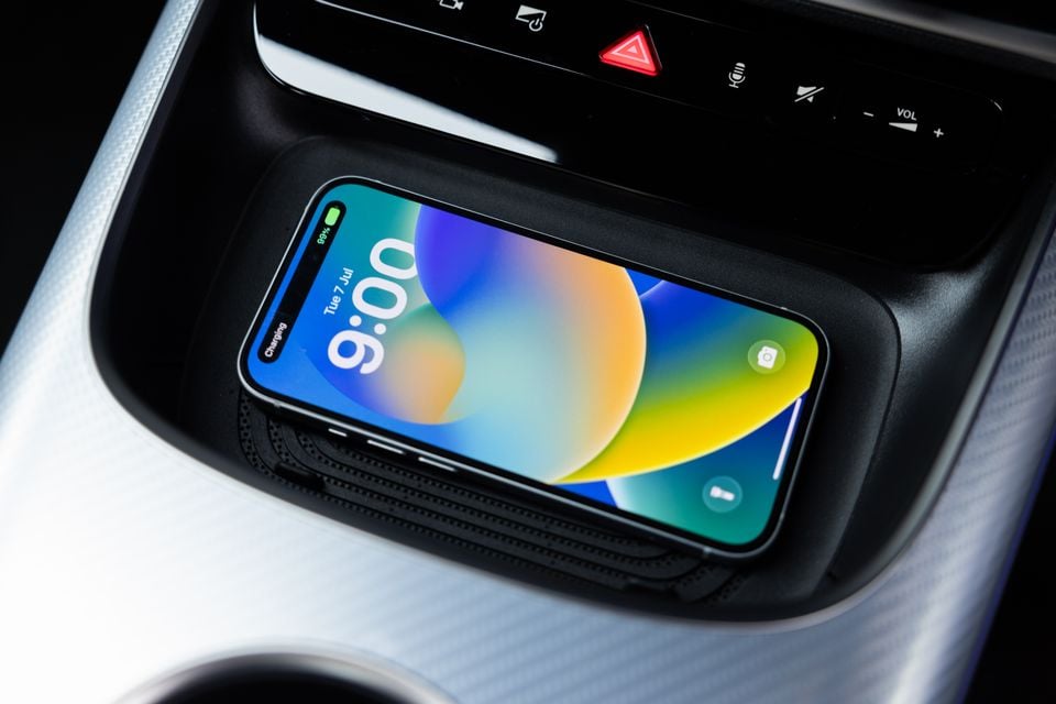 An iPhone charging wirelessly on the centre console wireless charging pad of a 2026 Mercedes-Benz CLA 250 Electric
