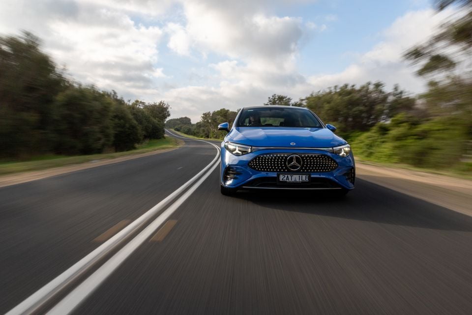 A blue Mercedes-Benz CLA electric sedan seen from the front while driving on a country road in Australia