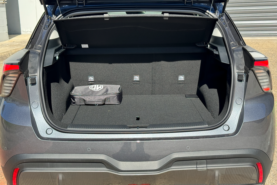 Open boot of a grey MG4 EV SUV showing the carpeted cargo area with an MG-branded bag inside