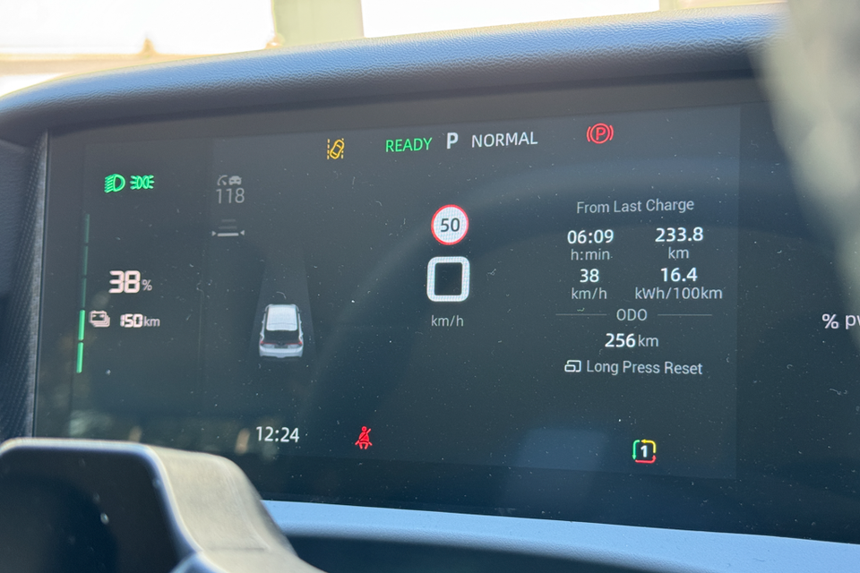 The digital instrument cluster of an MG4 EV showing battery charge at 38%, 150km estimated range, trip data from last charge including 233.8km travelled at 16.4kWh/100km, and a 50km/h speed sign alert on screen.