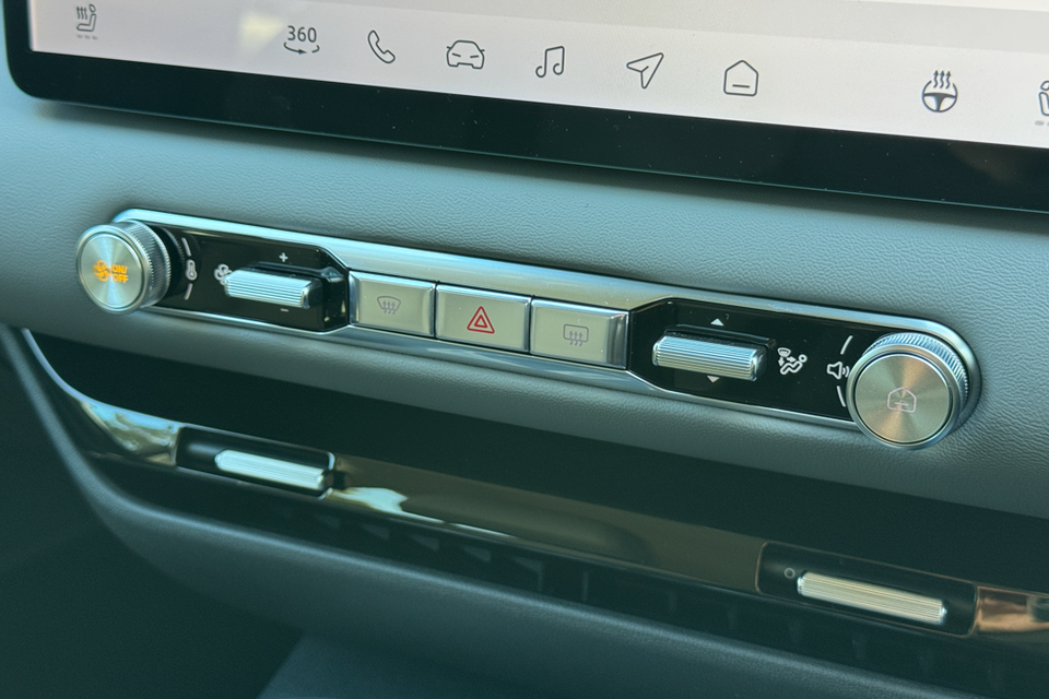 Close-up of the climate control and shortcut button strip below the touchscreen inside a 2026 MG 4 EV Essence, showing physical dials and hazard light controls