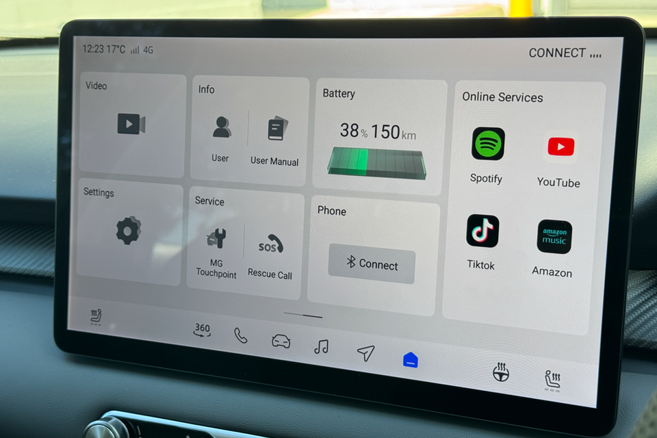 The touchscreen infotainment display of an MG4 EV showing the home screen with battery status at 38% and 150km range, online services including Spotify, YouTube, TikTok and Amazon Music, and options for phone connectivity and settings