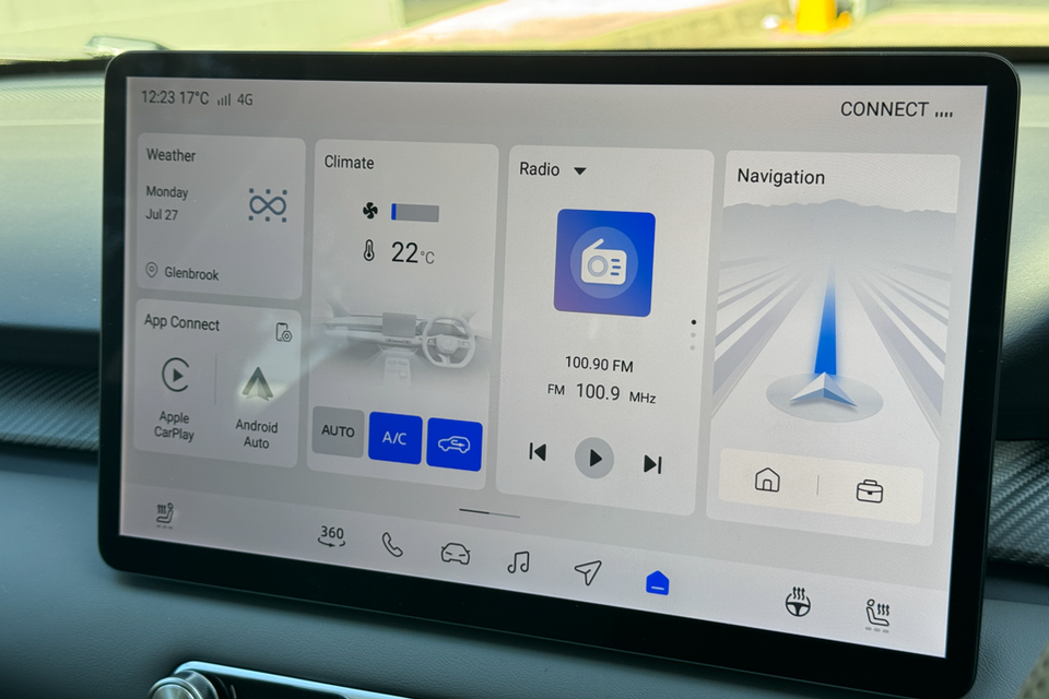 The infotainment touchscreen of a 2026 MG 4 EV showing the home screen with climate control, radio, navigation, weather, and Apple CarPlay and Android Auto options