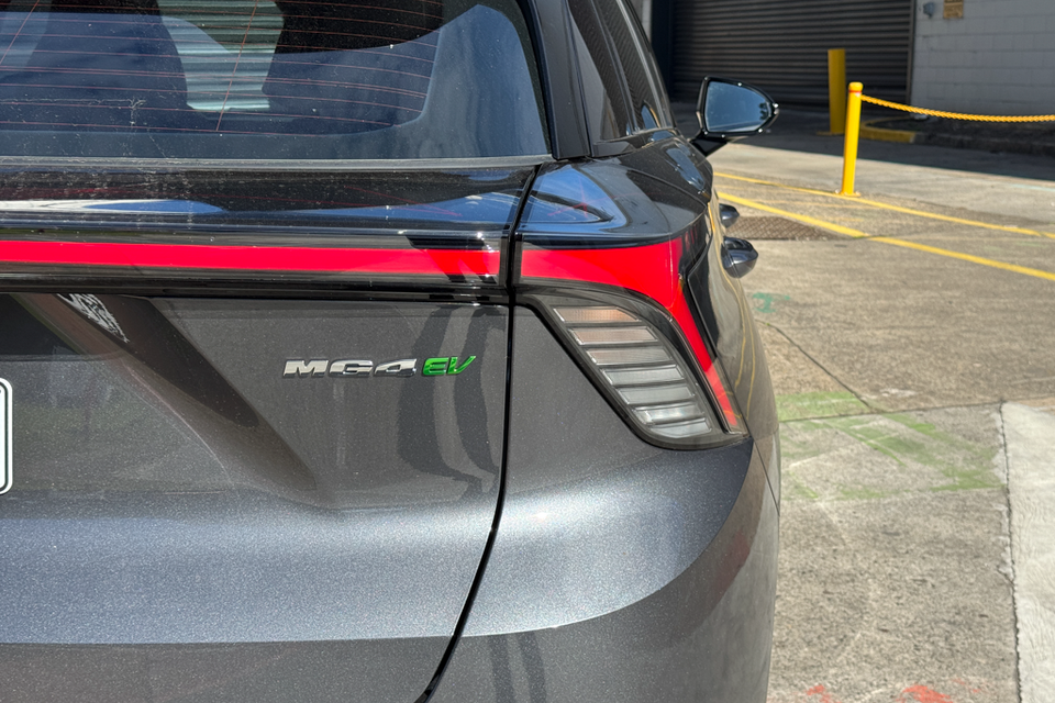 Close-up of the rear quarter panel and tail light of a grey MG4 EV, showing the MG4 EV badge and red tail light strip