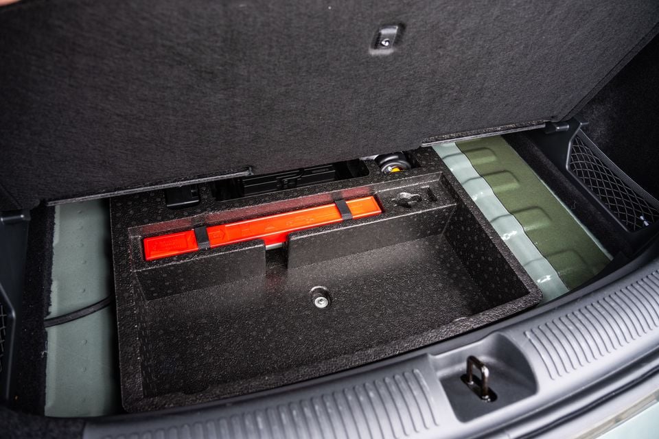 The under-floor storage compartment of a 2026 MG ZS Essence Hybrid boot, open to reveal a toolkit with red warning triangles and a spare wheel well area