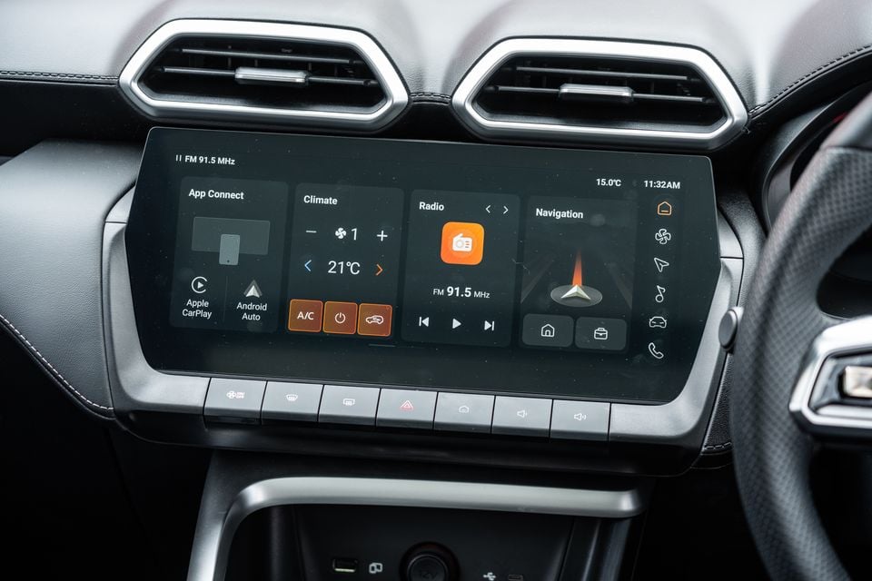 Close-up of the touchscreen infotainment system in a 2026 MG ZS Essence Hybrid, showing App Connect with Apple CarPlay and Android Auto, climate control set to 21°C, FM radio, and navigation panels