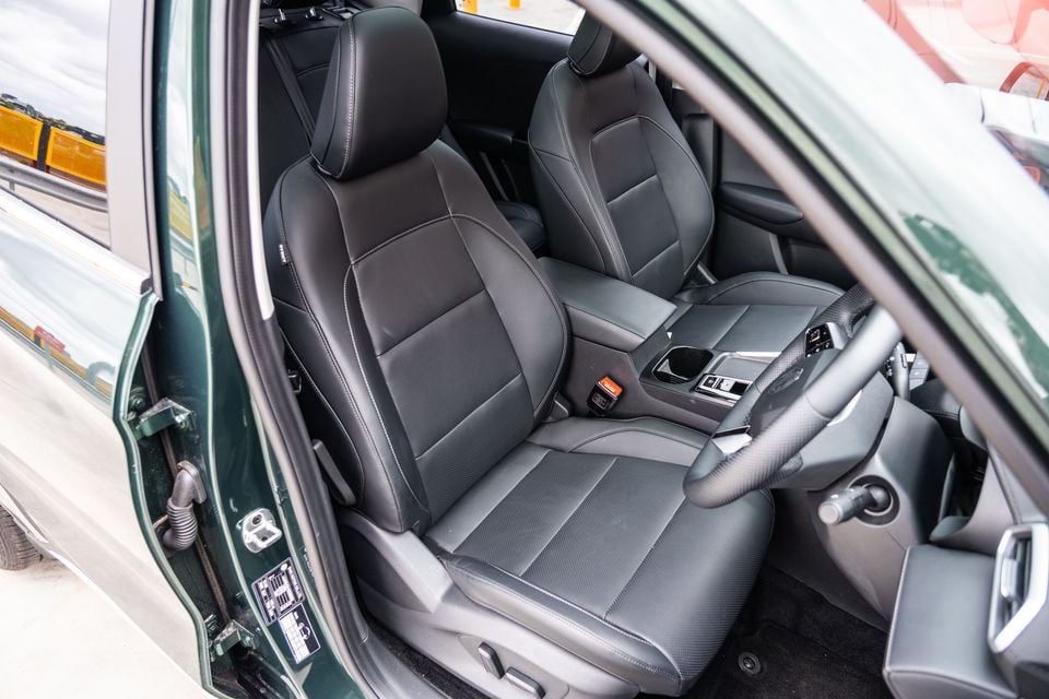 Dark leather front seats of a green 2026 MG ZS Essence Hybrid, viewed through the open driver's door