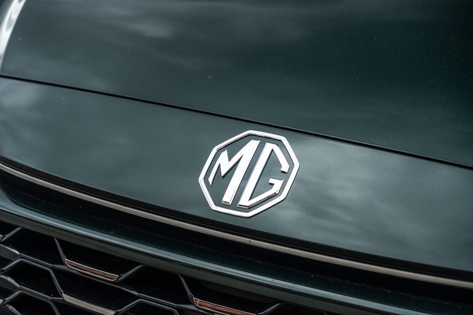 Close-up of the MG badge on the front grille of a dark green MG ZS hybrid
