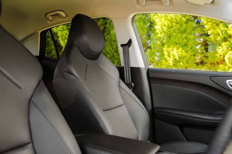 Grey leather front passenger seat interior of the 2026 MG4 Urban EV, with seatbelt and window showing green trees outside