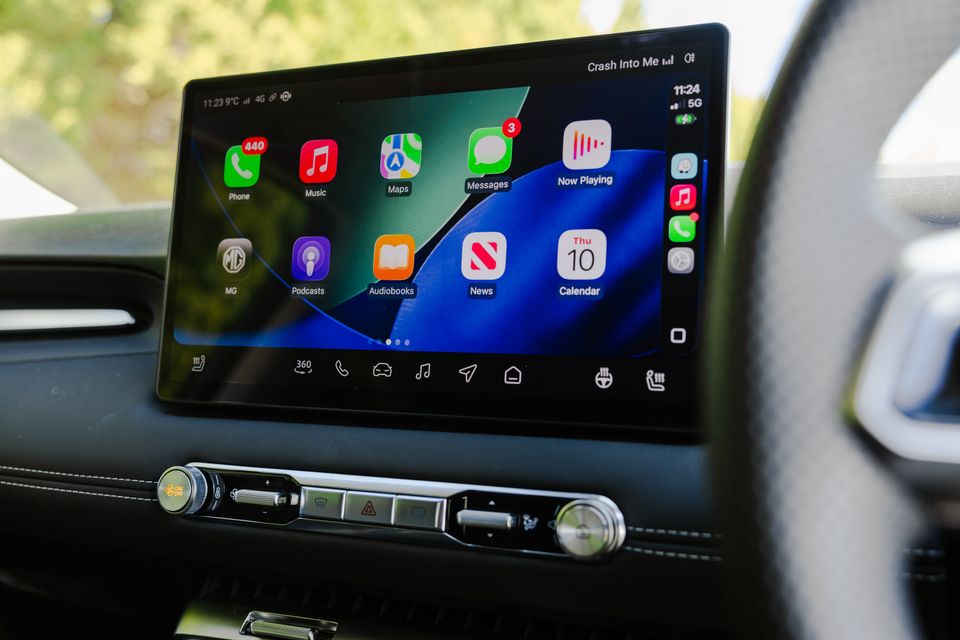 The infotainment touchscreen in an MG4 displaying Apple CarPlay with apps including Phone, Music, Maps, Messages and Podcasts visible