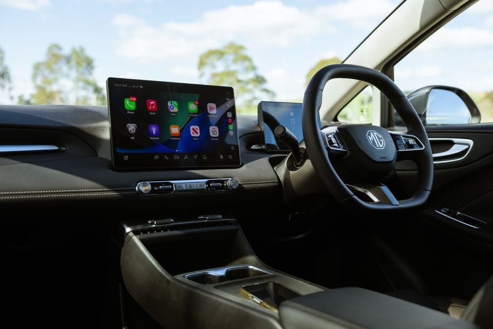 Interior of an MG4 Urban EV showing the central touchscreen displaying Apple CarPlay, a secondary driver's display, steering wheel with MG logo, and centre console