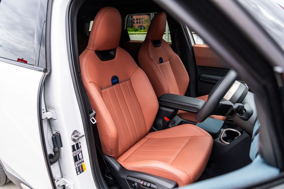 Tan leather front seats of a 2026 Mini Countryman SE Favoured, viewed from the open driver's door