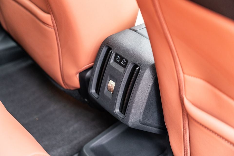 Rear air vents and USB charging ports mounted under the front seat of the 2026 Mini Countryman SE Favoured, with tan leather seats and dark carpet visible
