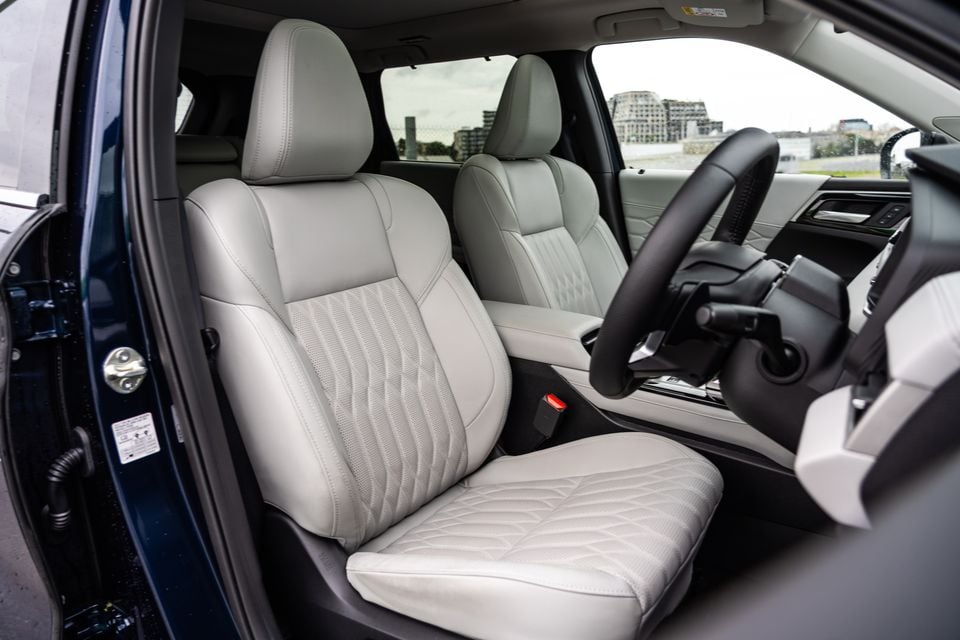 Light grey leather front seats of a 2026 Mitsubishi Outlander Exceed PHEV, viewed from the open driver's door