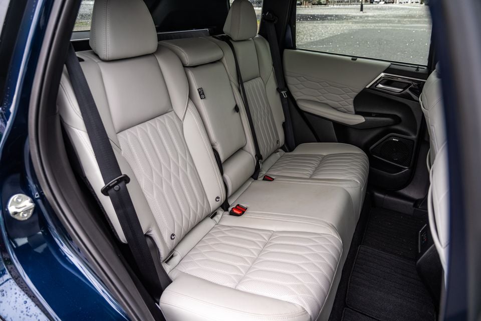 The rear seats of a 2026 Mitsubishi Outlander PHEV with light grey quilted leather upholstery, viewed through the open rear door