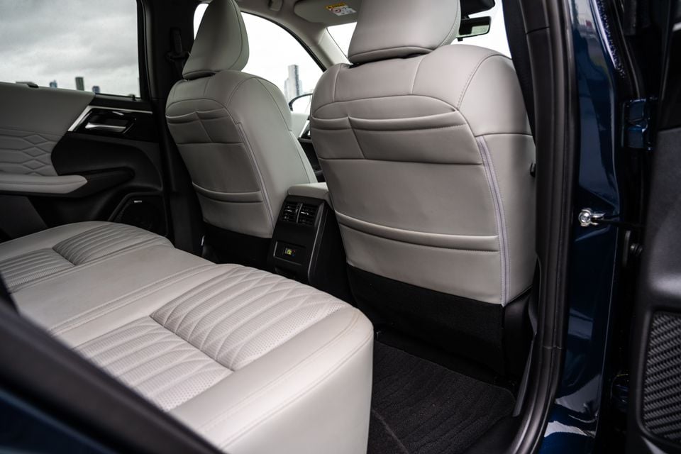 Rear interior of a 2026 Mitsubishi Outlander PHEV showing light grey leather second-row seats with rear climate controls on the back of the centre console