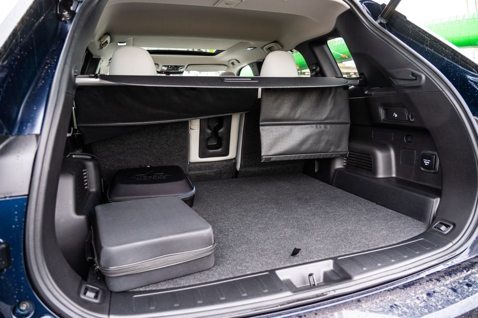 Boot of a 2026 Mitsubishi Outlander PHEV SUV open from the rear, showing a spacious carpeted cargo area with a small bag and storage accessories