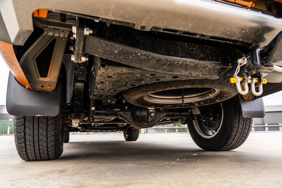 Underside of a 2026 Mitsubishi Triton GSR ute seen from behind, showing the spare wheel, rear axle, tow recovery shackles and mud flaps