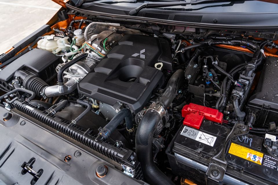 Engine bay of a 2026 Mitsubishi Triton GSR showing the turbo-diesel engine cover with Mitsubishi logo, battery and hoses