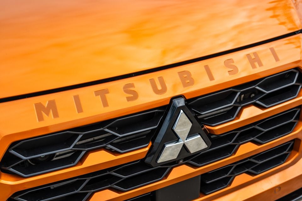 Close-up of the orange 2026 Mitsubishi Triton GSR's black grille with chrome three-diamond badge and Mitsubishi lettering on the bonnet