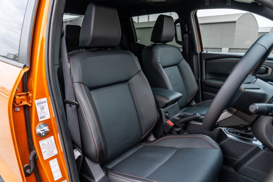 Black leather front seats with orange contrast stitching in the 2026 Mitsubishi Triton GSR, seen through the open passenger door
