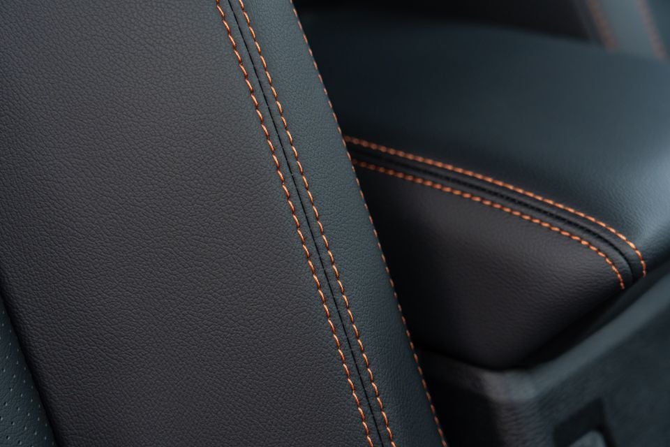 Close-up of black leather seat upholstery with orange contrast stitching and centre armrest in the 2026 Mitsubishi Triton GSR