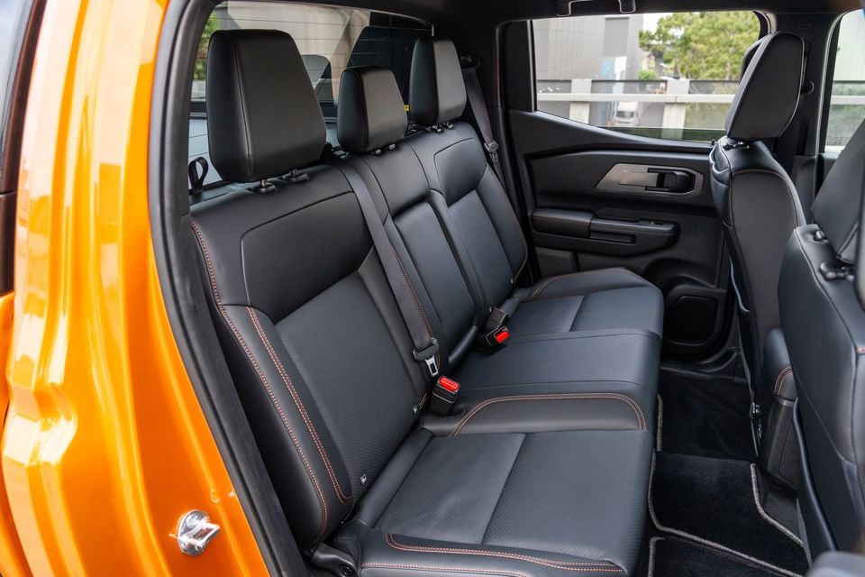 Rear bench seat of a 2026 Mitsubishi Triton GSR with black leather upholstery and orange stitching, seen through the open rear door