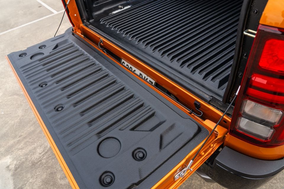 Open tailgate and lined tray of an orange 2026 Mitsubishi Triton GSR ute, with the rear tail-light visible