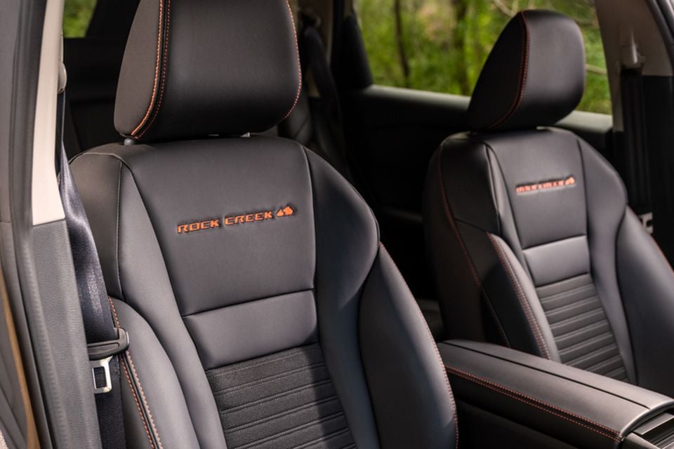 Black leather front seats of a 2026 Nissan Rogue Rock Creek Edition with orange stitching and Rock Creek badging embroidered on the headrests