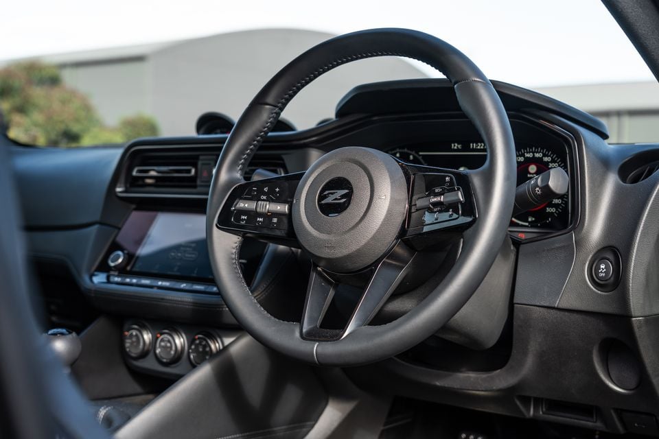 Nissan Z steering wheel and instrument cluster, showing the Z badge, multifunction controls, and digital driver display