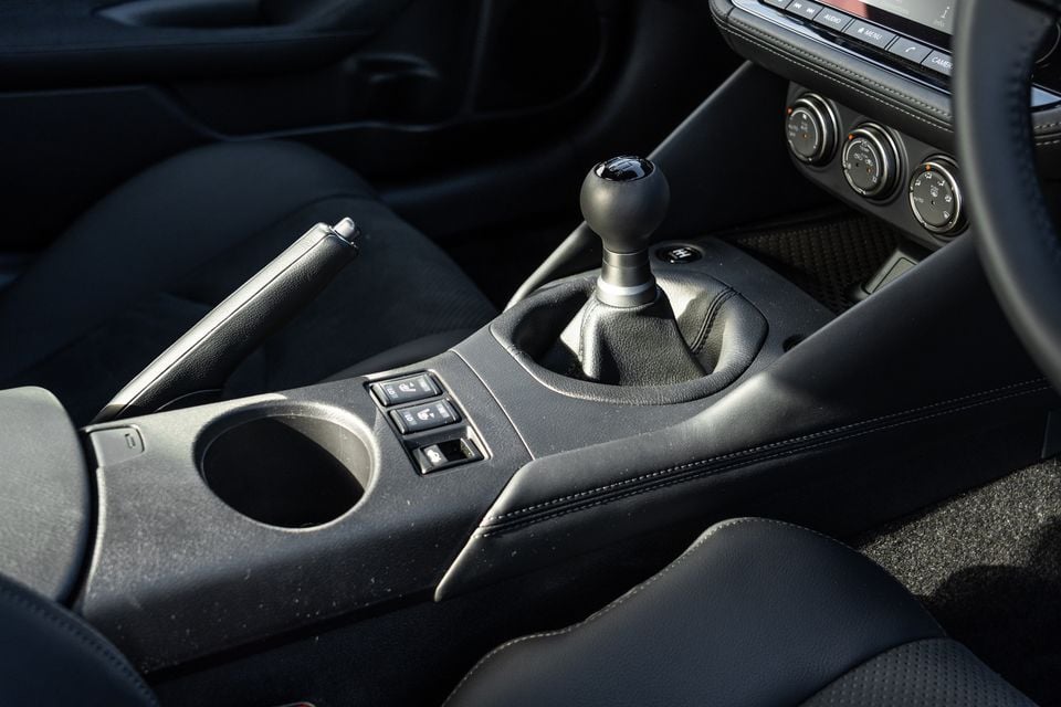 Close-up of the manual gear shifter and centre console inside a 2026 Nissan Z, showing the handbrake, cup holder, and climate controls