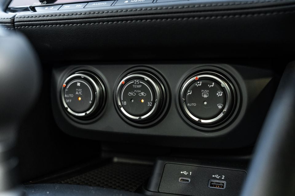 Close-up of the climate control dials and USB ports on the centre console of a Nissan Z, showing temperature, fan speed and airflow controls