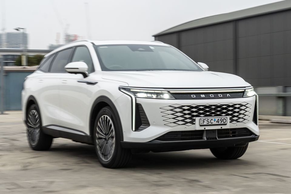 Um SUV Omoda 9 branco visto de um ângulo frontal de três quartos em um ambiente urbano