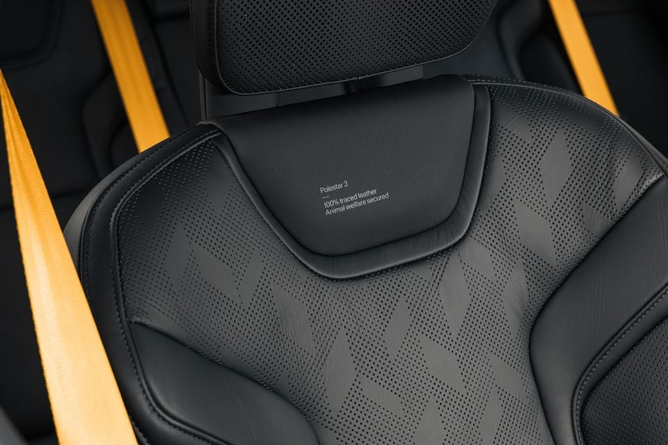 Close-up of a Polestar 3 black leather seat with a diamond-pattern design and yellow accent stripes, labelled '100% traced leather, Animal welfare secured'