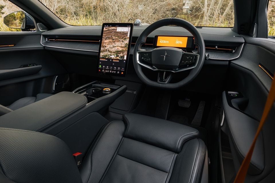 Interior of a 2026 Polestar 3 showing the large portrait touchscreen with Google Maps, steering wheel with Polestar logo, and digital instrument cluster displaying 420km range at 86% charge, with dark upholstery and orange accent lighting
