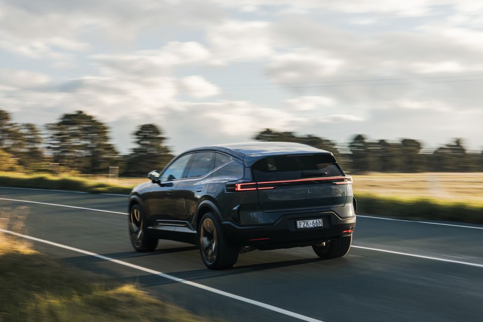 A dark-coloured 2026 Polestar 3 SUV seen from the rear three-quarter angle while driving on a rural Australian road