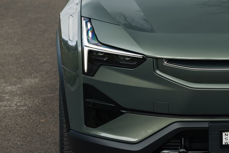 Close-up of the front headlight and bumper on a green Polestar 3 SUV