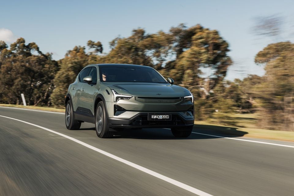 A green Polestar 3 SUV driving on a road in Australia, seen from the front