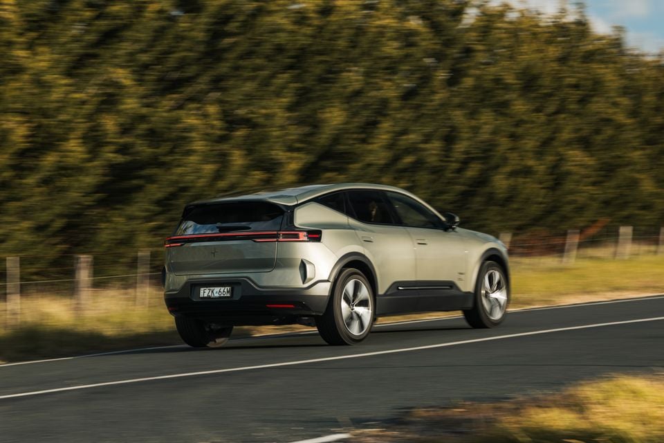 A silver 2026 Polestar 3 SUV seen from the rear three-quarter angle while driving on a country road