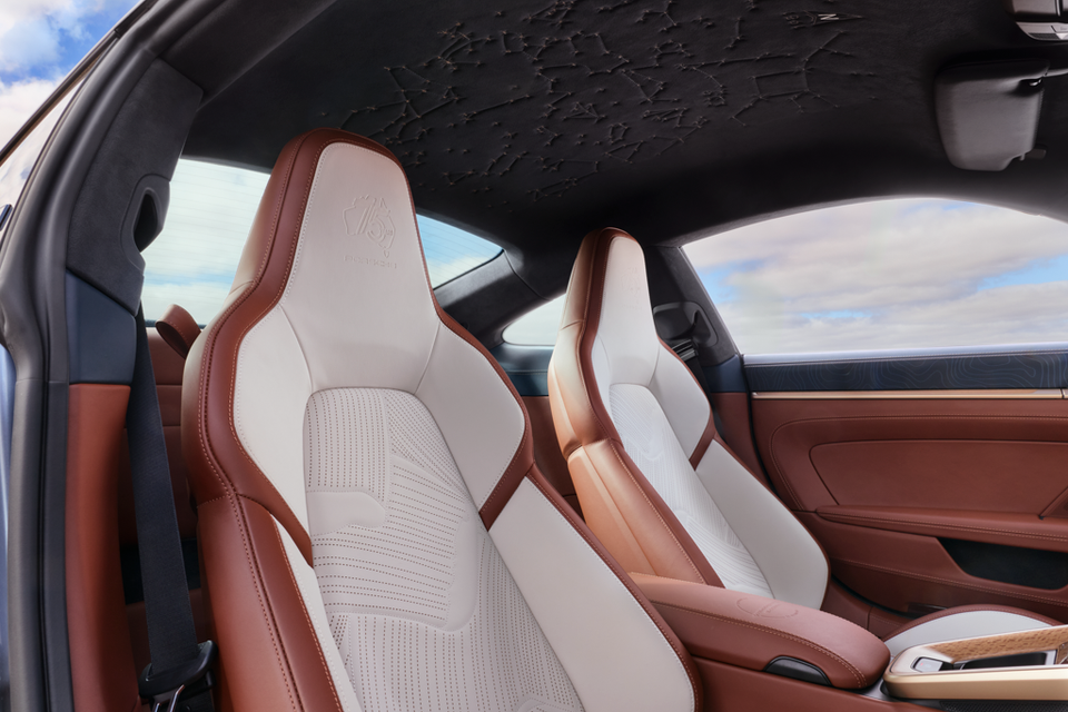 Two-tone tan and cream leather bucket seats inside a 2026 Porsche 911 Turbo S, with a textured dark headliner overhead