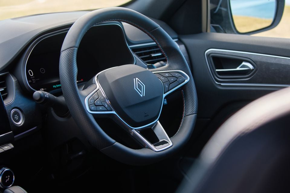Renault Arkana interior showing the leather-wrapped steering wheel with Renault logo, driver instrument cluster, and dashboard controls