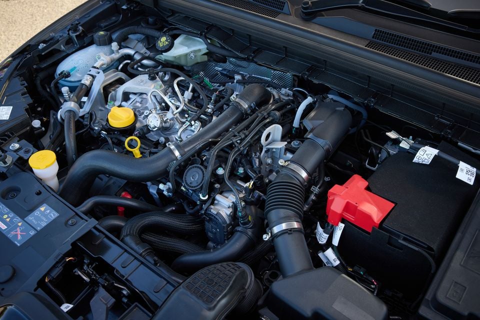 The engine bay of a 2026 Renault Arkana showing its turbocharged petrol engine with various hoses, fluid reservoirs and a red battery terminal cover