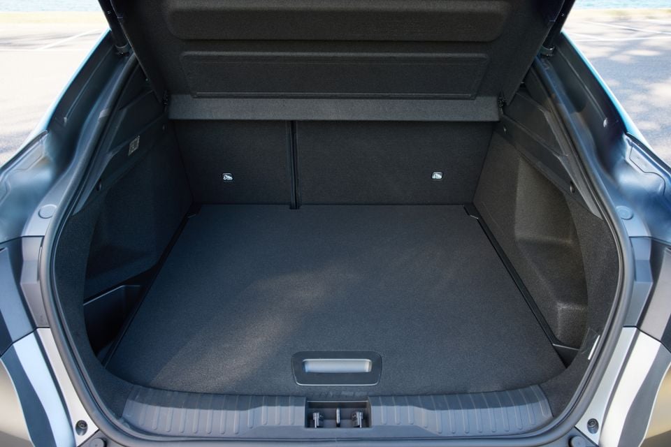 The empty boot of a 2026 Renault Arkana SUV, showing a flat carpeted load floor with a lift handle and rear seat fold levers.