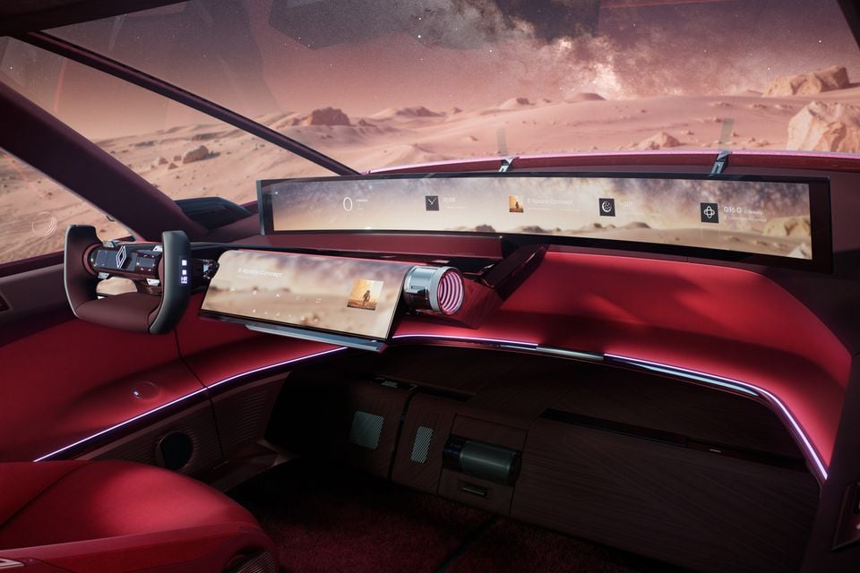 Red interior of the 2026 Renault E-Space Concept with a yoke steering wheel, wide curved screens and ambient lighting, against a Mars-like desert backdrop