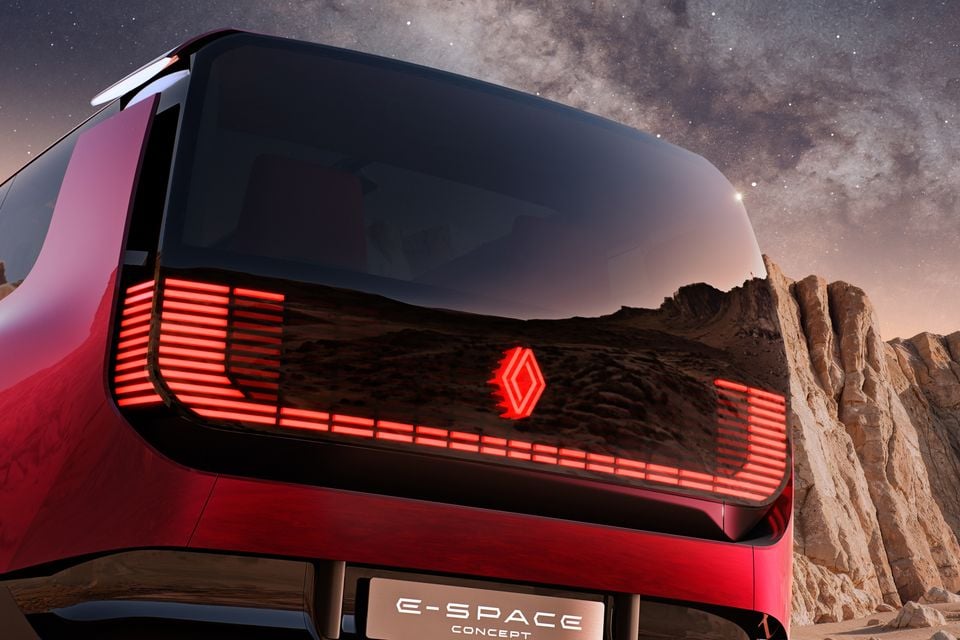Red 2026 Renault E-Space Concept seen from the rear, with illuminated red tail-lights and badge, beneath a starry night sky beside rocky cliffs