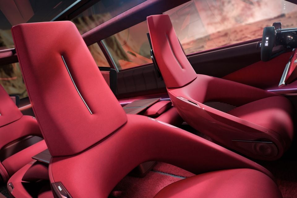 Red sculpted front and rear seats inside the 2026 Renault concept, with a yoke-style steering wheel and a desert scene through the windows