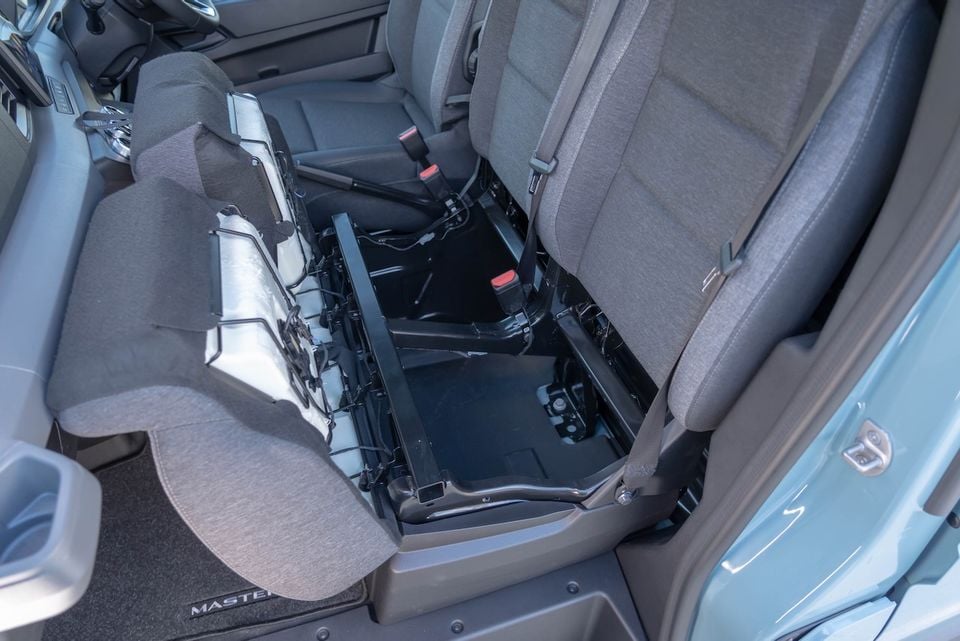 Interior of the 2026 Renault Master van showing a middle-row seat folded forward to reveal under-seat storage space